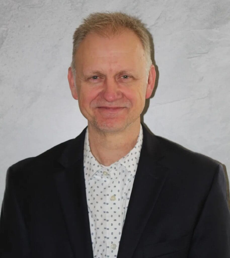 A man in a suit and tie standing up against a wall.
