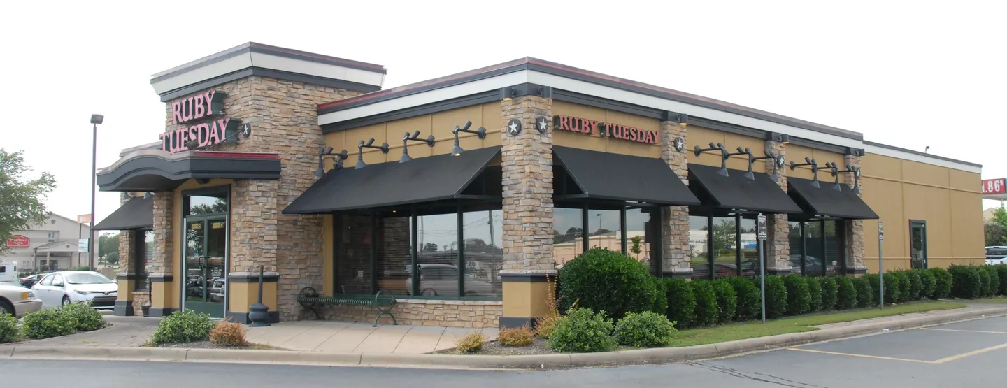 A restaurant with black awnings and brick walls.