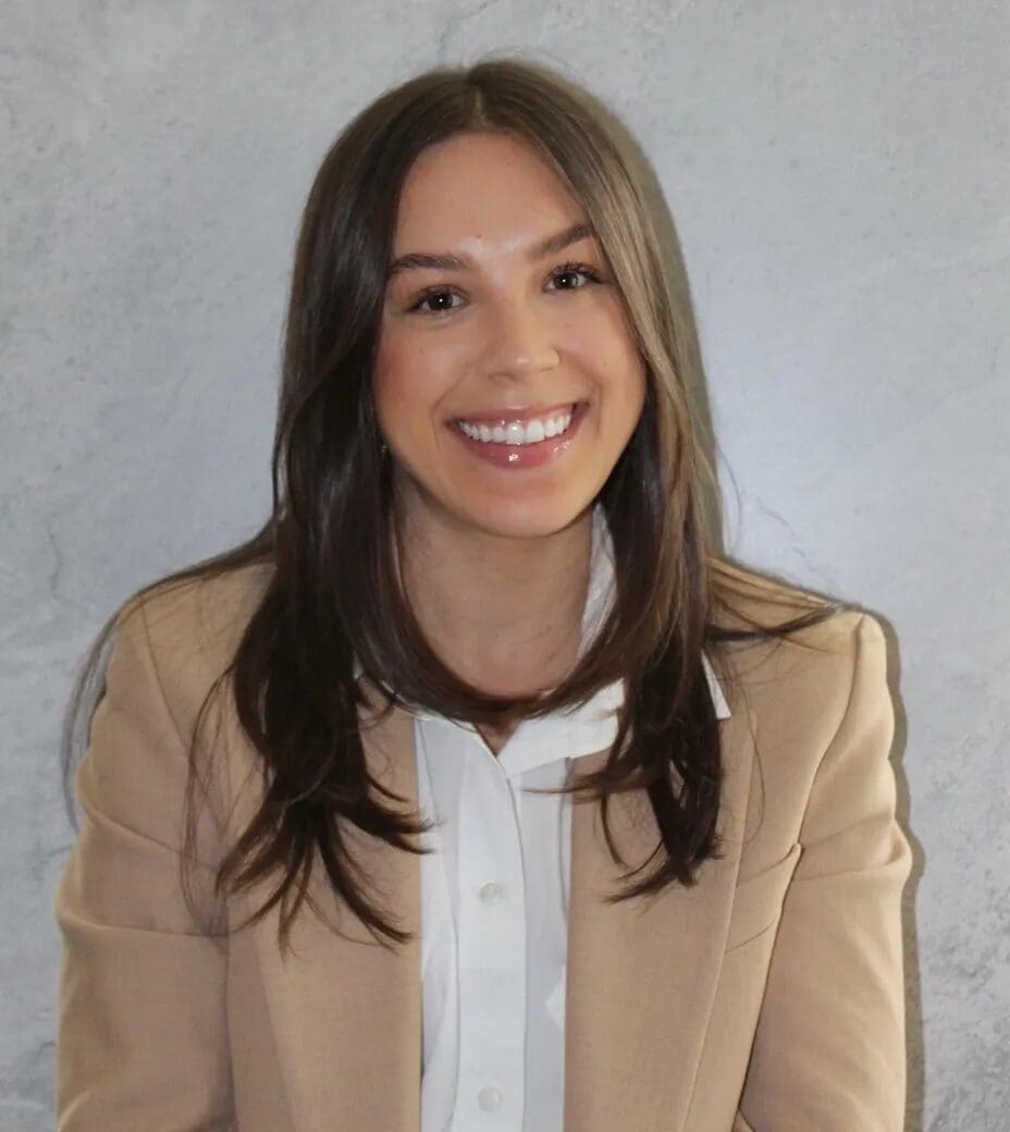 A woman in a beige jacket smiling for the camera.